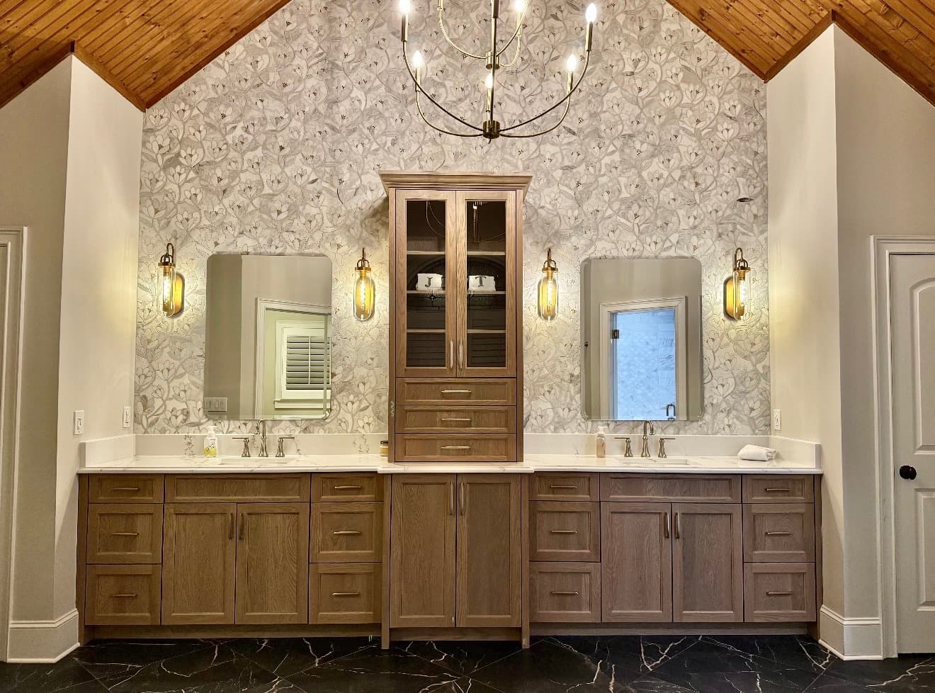 Finished double vanity with floral wallpaper accent wall and brass sconces
