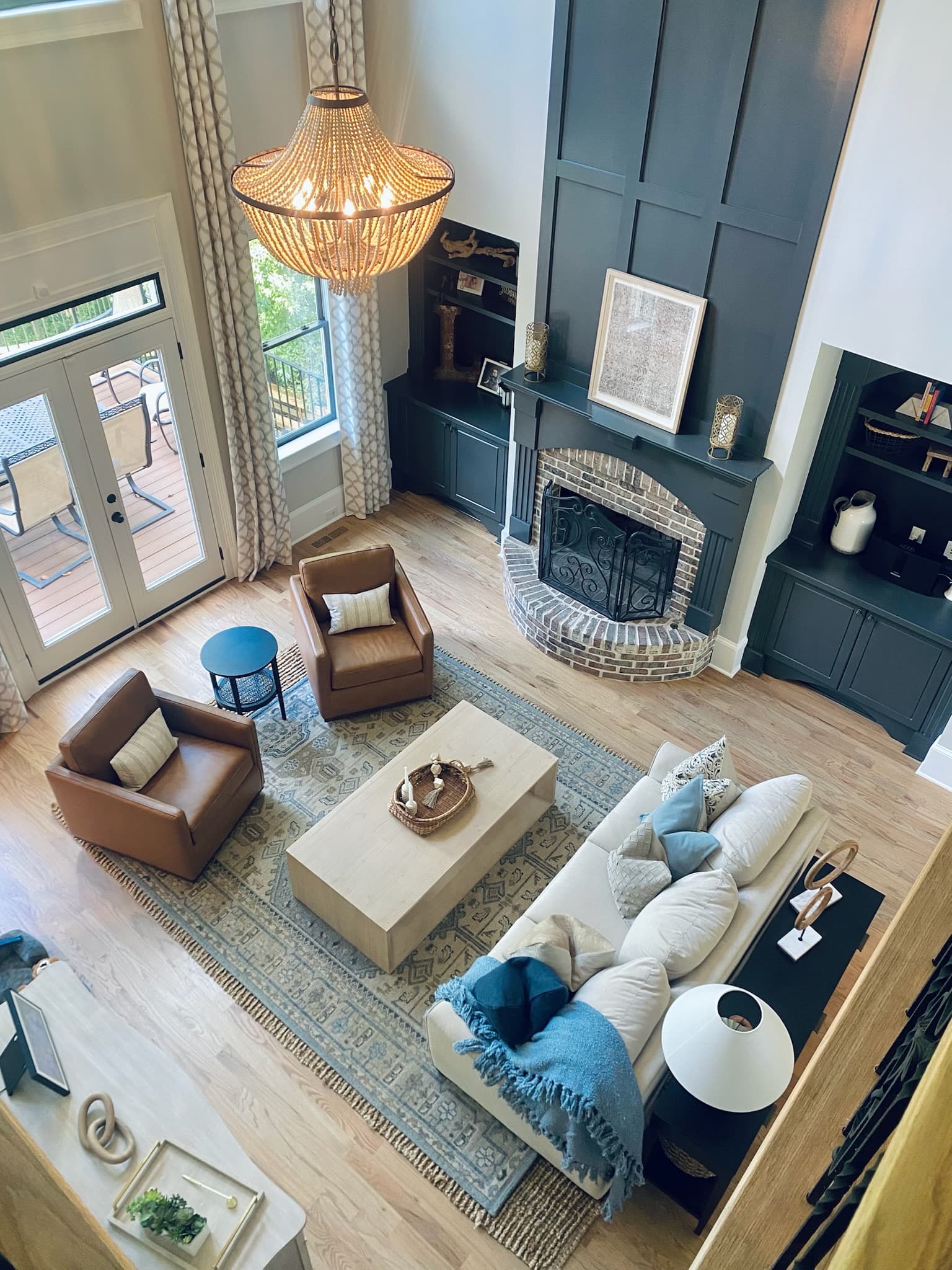 Two-story living room with a dark fireplace wall, built-in shelving, and a layered neutral rug
