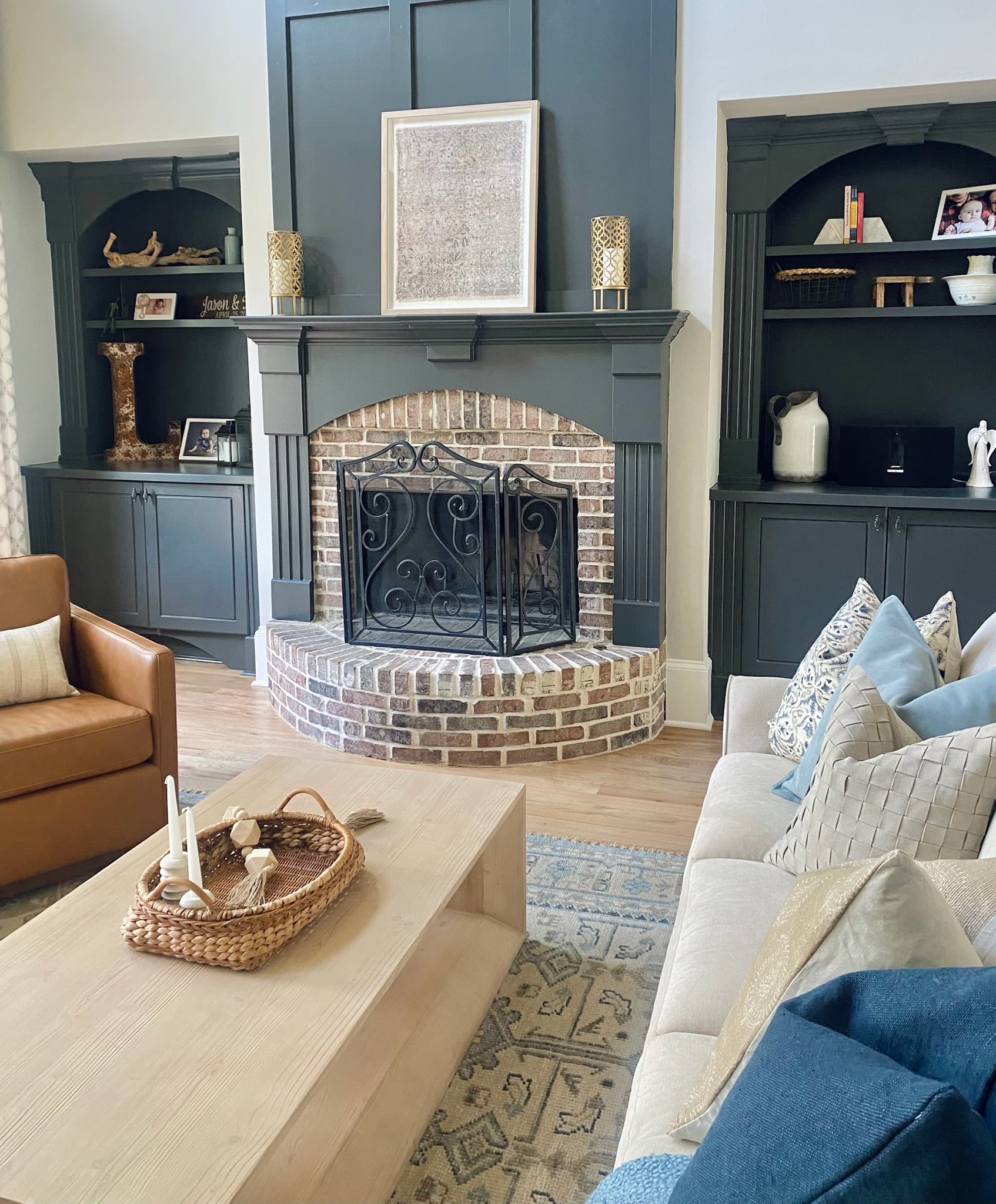Brick fireplace with a charcoal mantel flanked by matching dark built-in cabinetry and open shelving